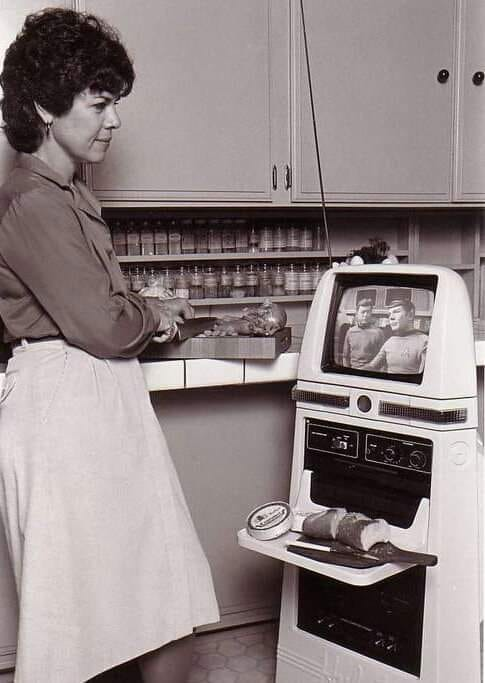 Woman in kitchen watching Star Trek on Hubot and food on Hubots tray.